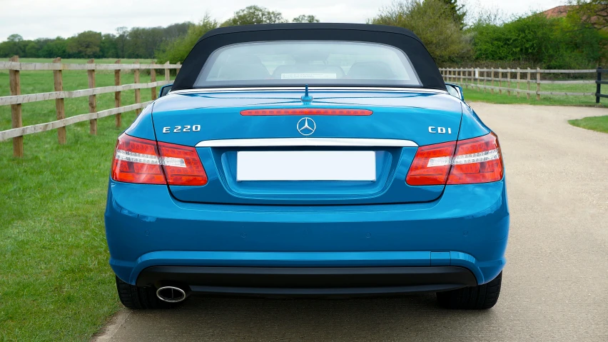 a blue mercedes clk cab in front of a fence