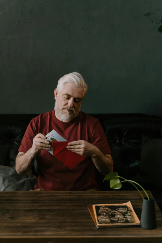 a man sitting on a leather couch with a red t shirt and red tie