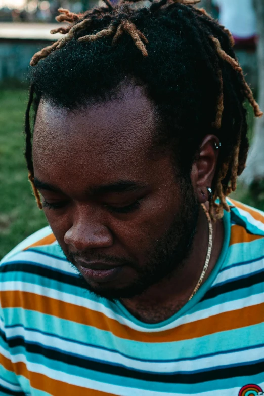 a man with dreadlocks has a yellow and blue striped shirt