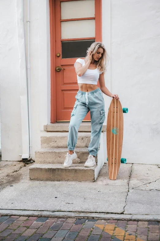 a girl in light wash jeans holds her skateboard