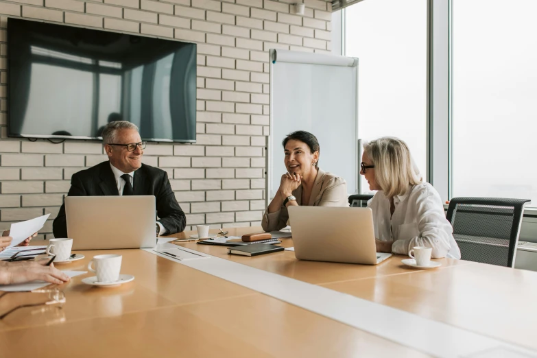 four people seated at a conference table are talking