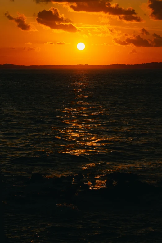 a large body of water under a sunset with the sun