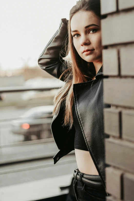 a beautiful woman leaning on a brick wall