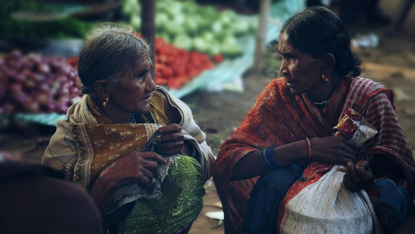 two women stand together while looking at their cell phone