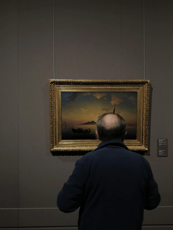 a man standing next to a painting hanging in the corner of a building