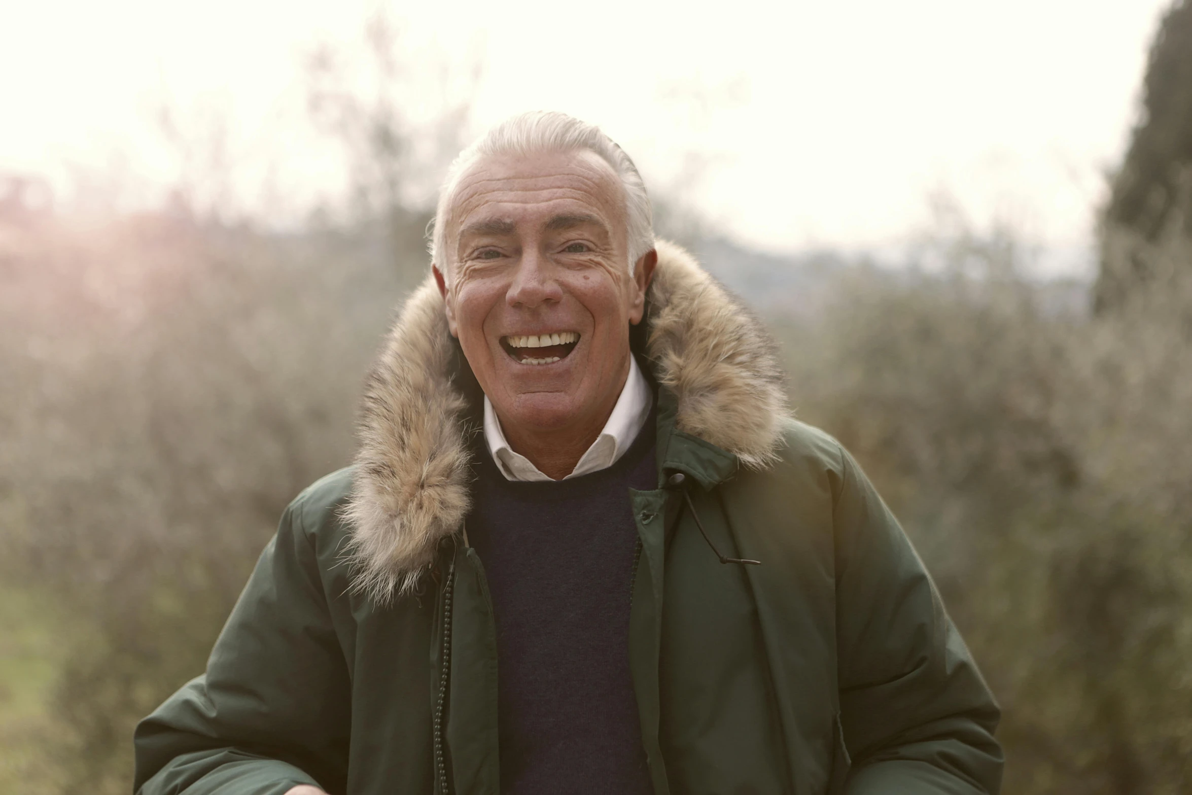 a man in a parka smiles and looks off to the side