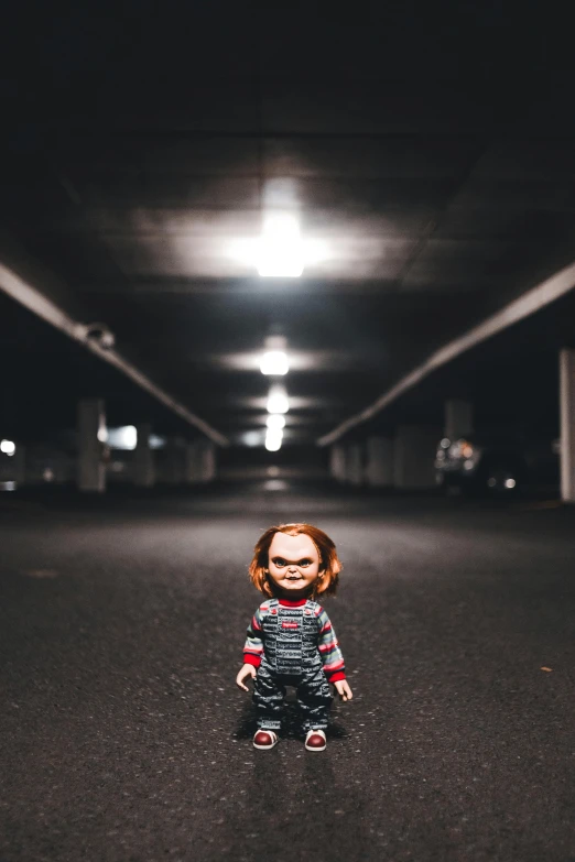 a doll sitting on the ground under a bridge