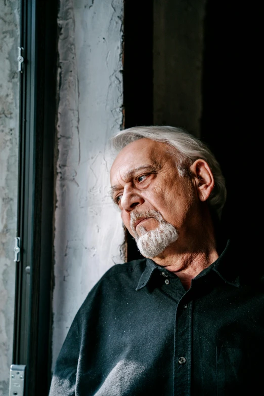 an older man looking out a window with white hair and greying