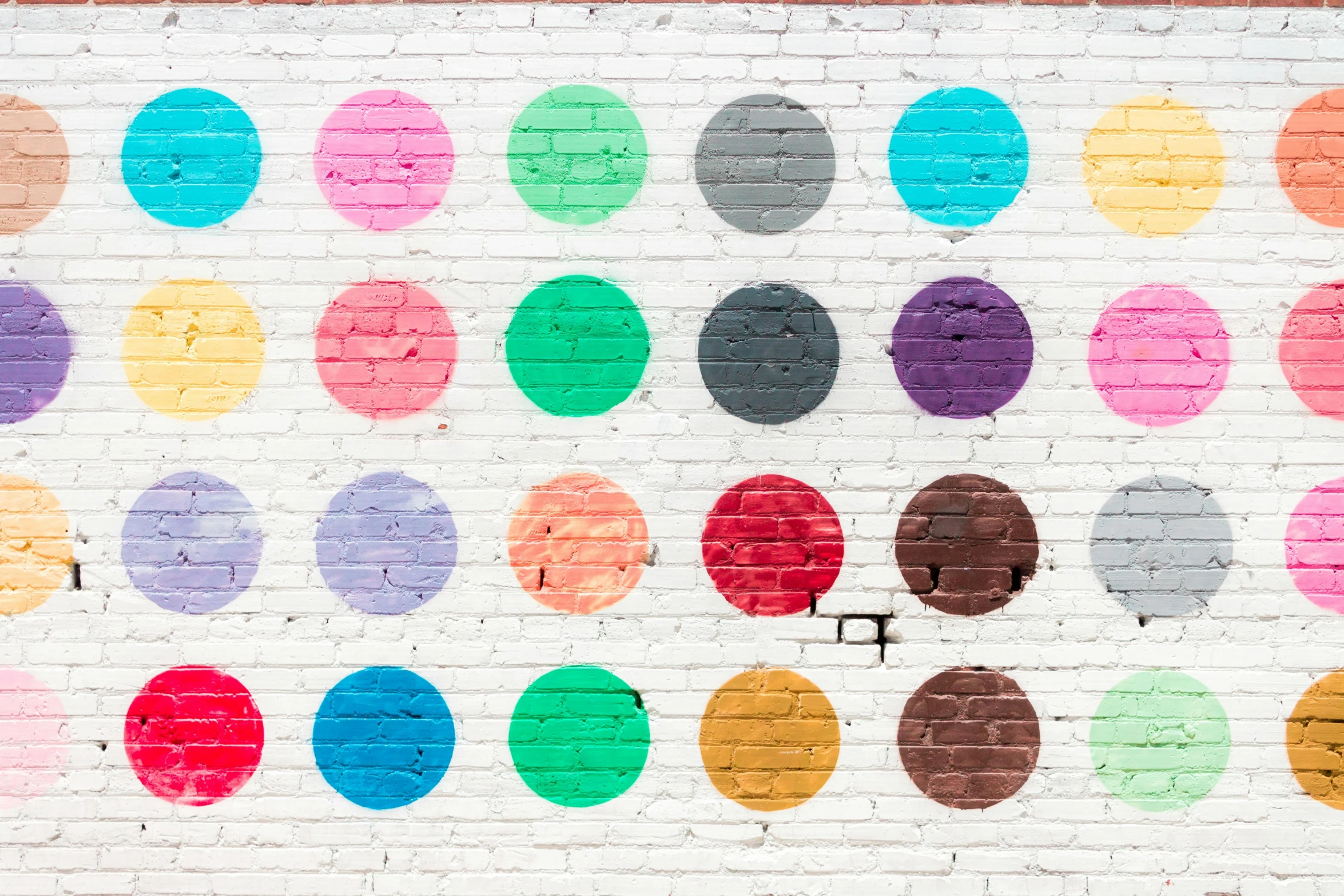 a white brick wall with colored polka dots painted on it