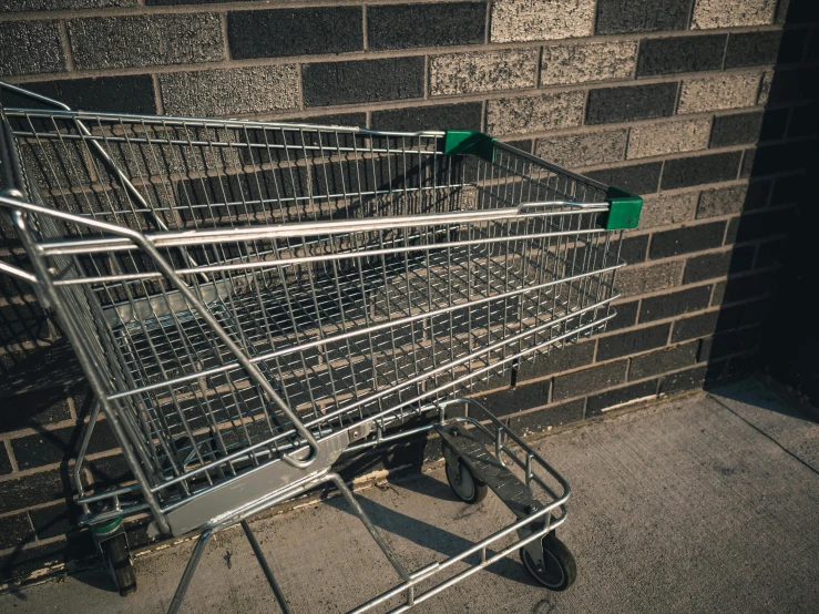 a shopping cart sits next to a brick wall