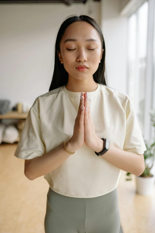 a woman in white shirt doing yoga with hands clasped