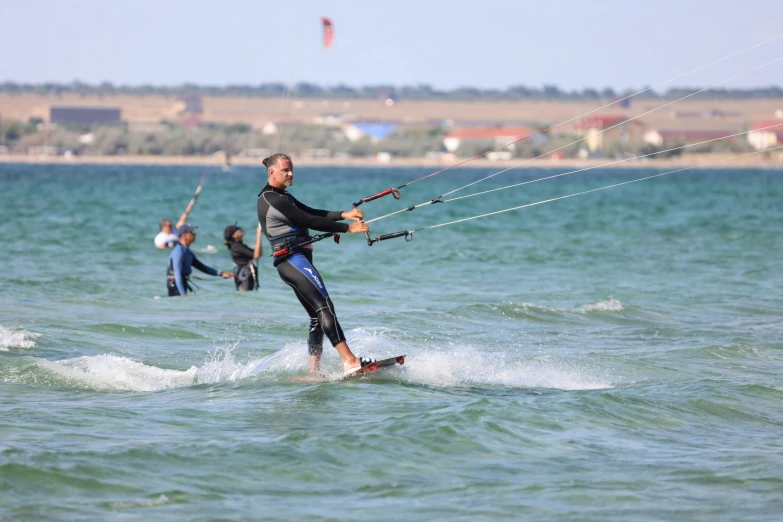 people in wetsuits wind surfing and being pulled through water by long ropes