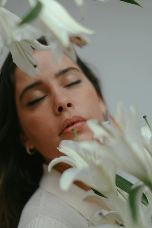 a young woman wearing white is holding a bunch of flowers