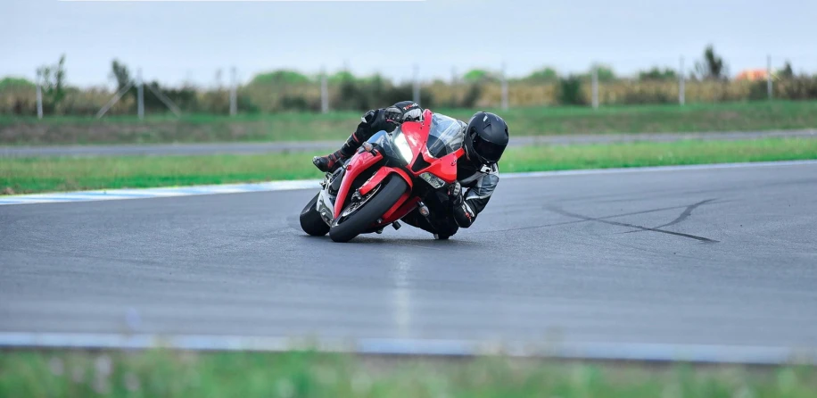 a person on a red and black motorcycle is going around a curve