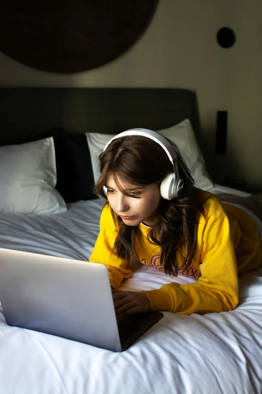 a girl in a yellow outfit and headphones is on her laptop computer