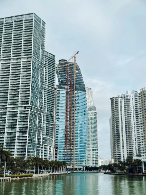 a few buildings under construction in a city next to a river