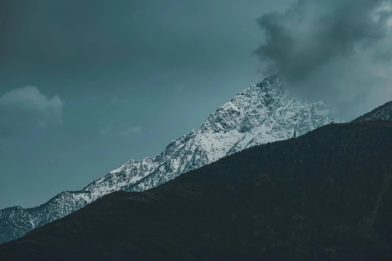 mountains are covered in snow on a cloudy day