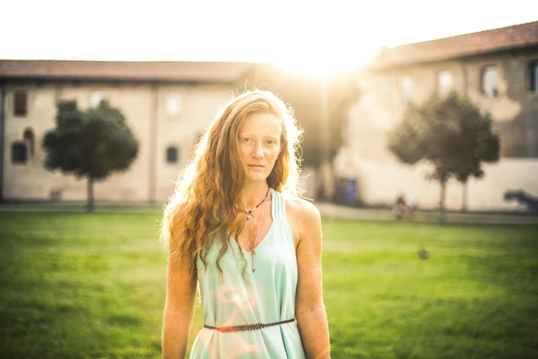 woman in dress standing near large building in sun