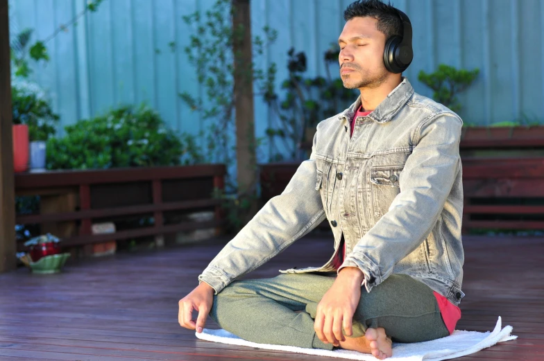 a man sits on a wooden deck with headphones on