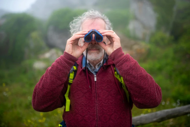 a man with greying hair looking through binoculars