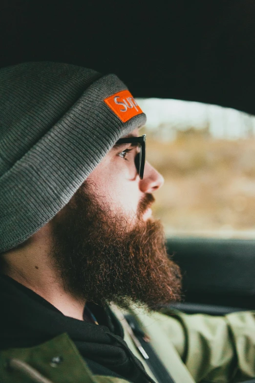 a bearded man wearing a grey hat with an orange patch