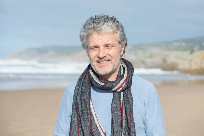 an older man is on the beach with his scarf over his head