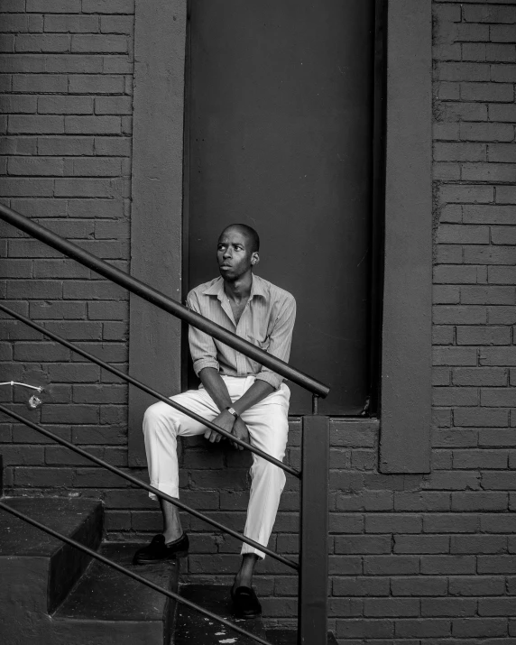 a man in shirt and pants sitting on the steps of a building