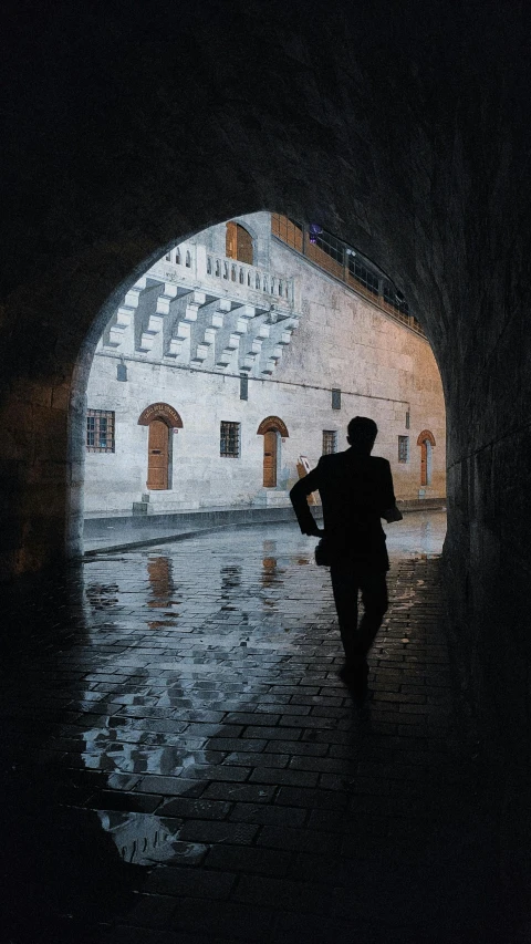 a person walking out of a tunnel on a cobblestone street