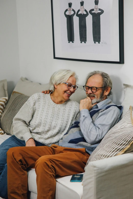 an older couple sitting on a sofa smiling