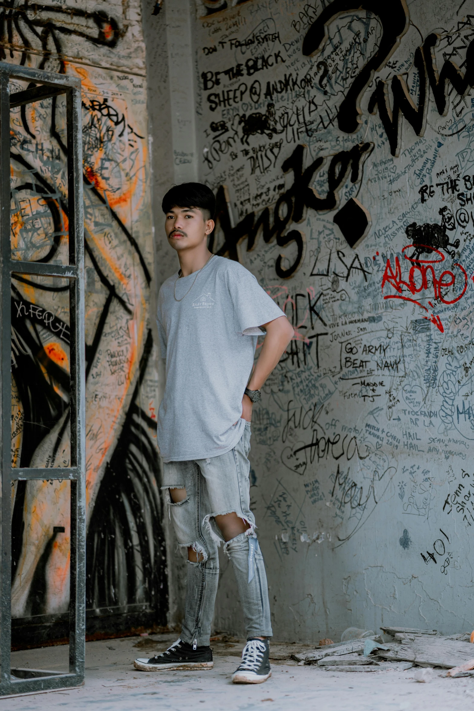 a young man standing in front of graffiti covered wall