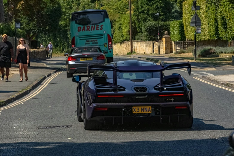 a black car driving down the street past two vehicles