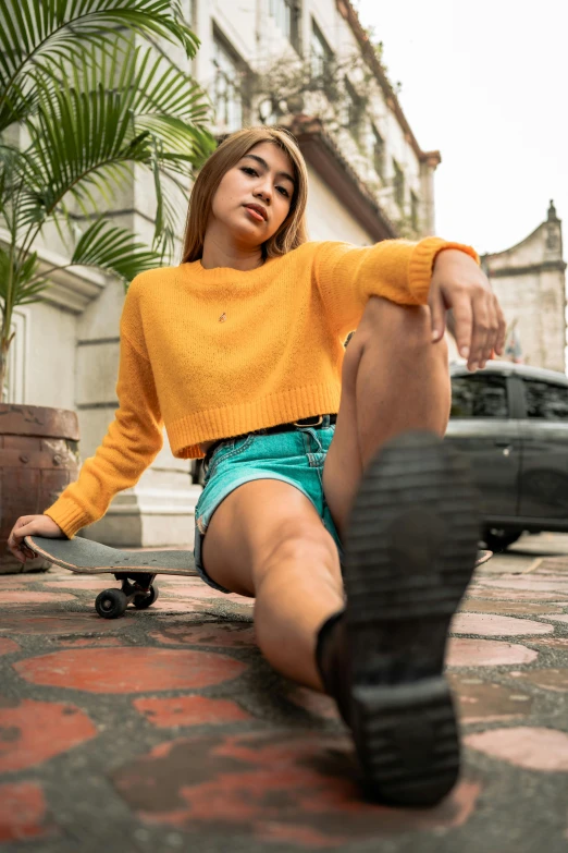 a beautiful woman sitting on top of a cement slab next to a skateboard