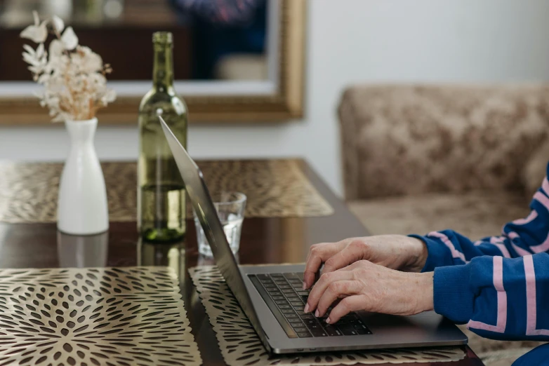 woman working on her laptop in front of a wine bottle