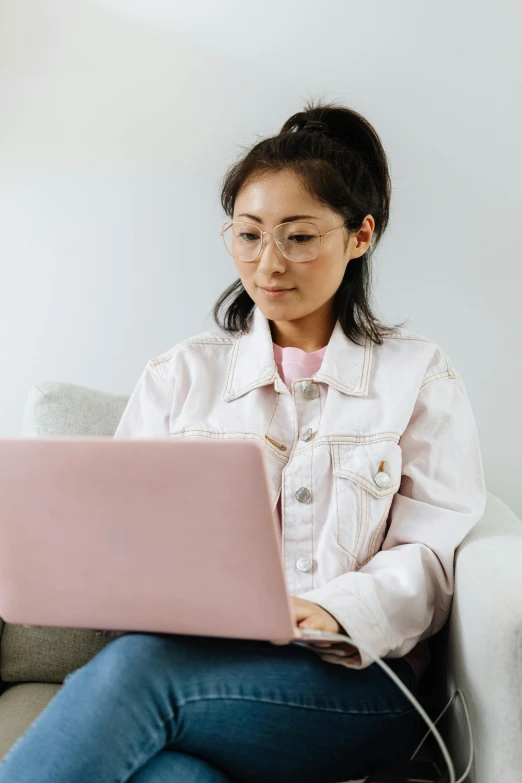 a girl sitting on a sofa using a laptop