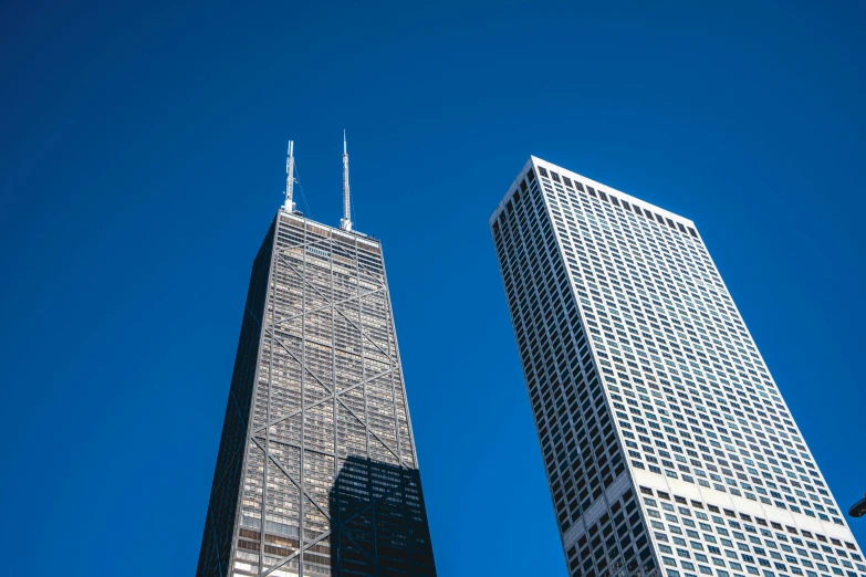 two tall buildings against a blue sky with clouds