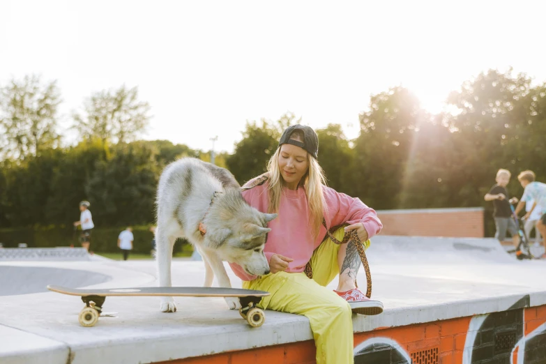 a man kneels next to a gray wolf at the skate park