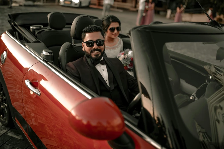 a man sitting in a red car wearing sunglasses