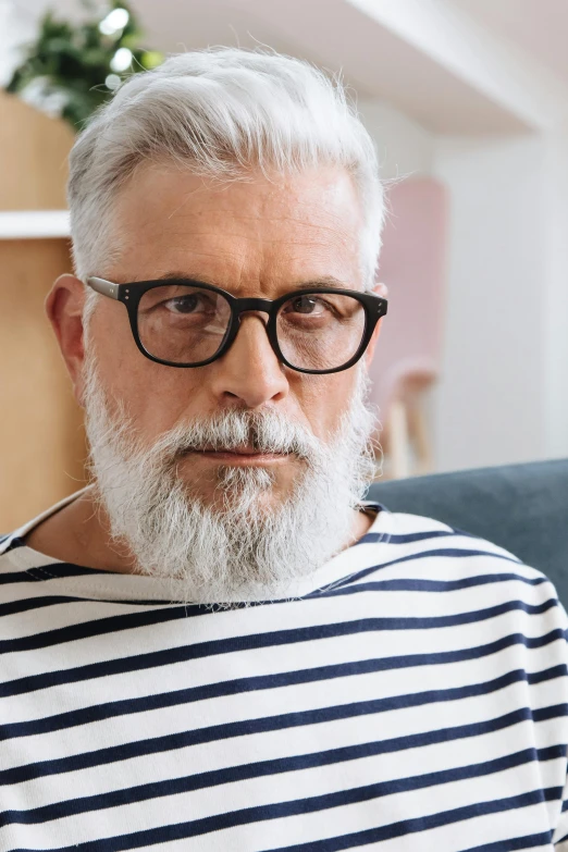 the older man is sitting with greying hair and black glasses