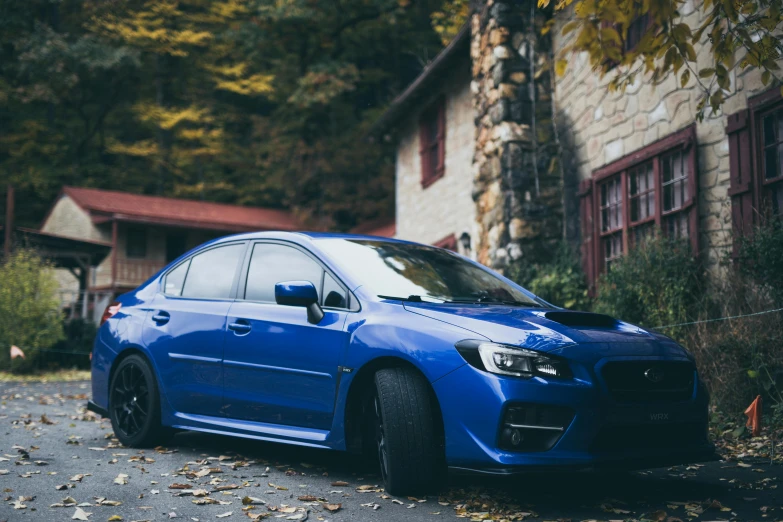 the blue car is parked on the street near a house