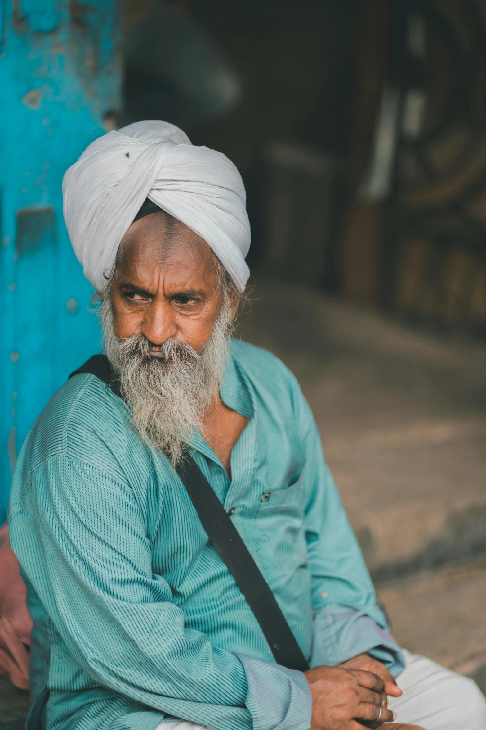 a bearded man wearing a blue shirt sitting down