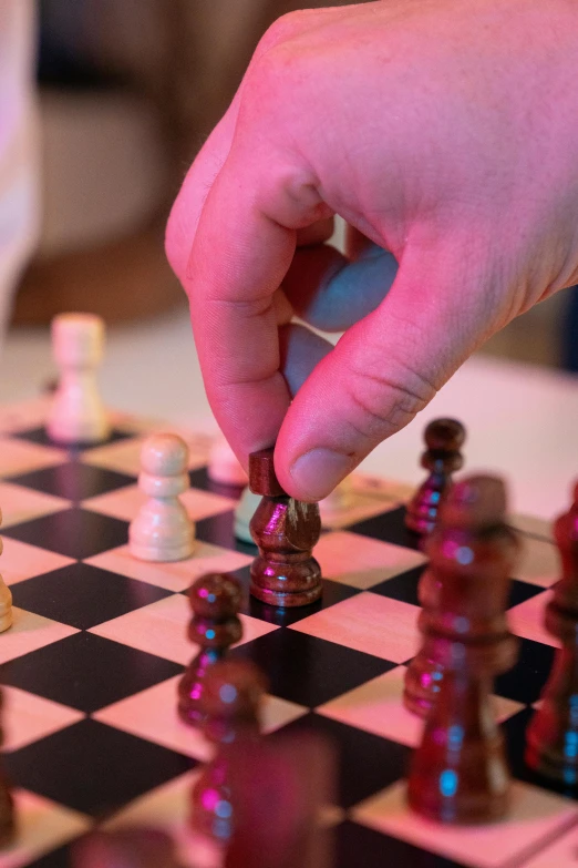 someone holding a piece in their hand as they play a game of chess