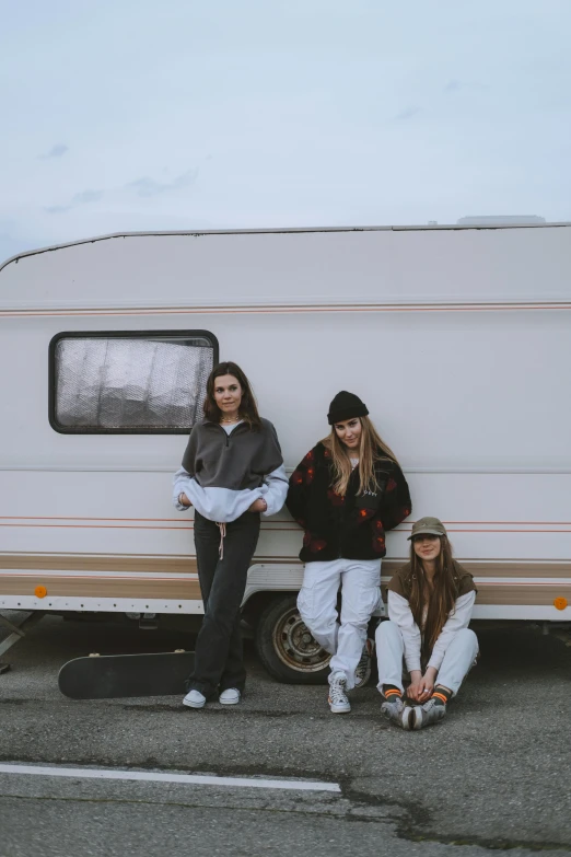 three people in front of a trailer are posing