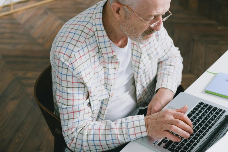 an older man is sitting at a table with his laptop