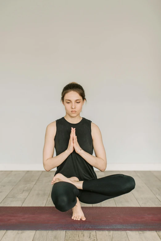 woman sitting on yoga mat with hands together in a cross position