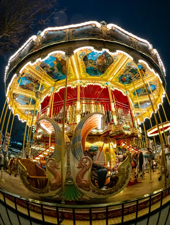 an outdoor carousel at night with a bright red roof and colorfully decorated umbrellas