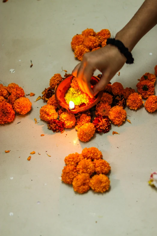 a person lighting a candle in some orange flowers