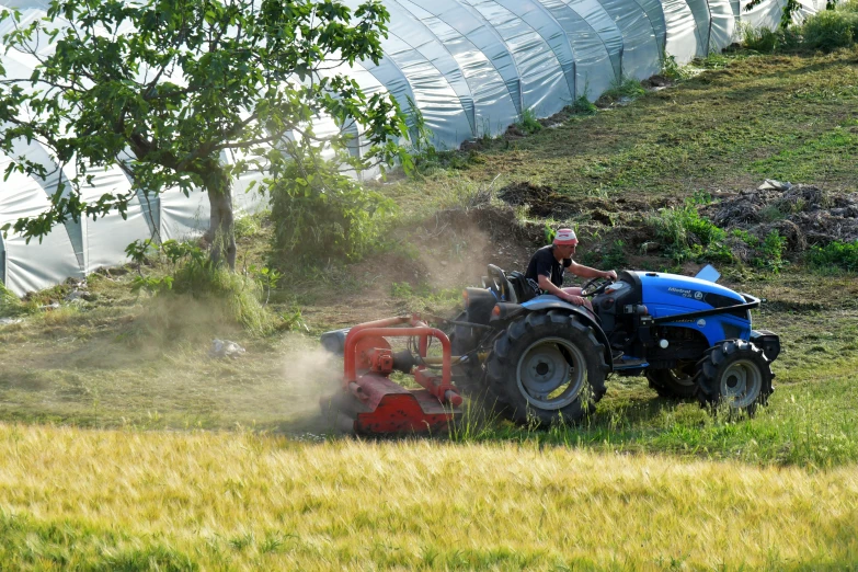 a farmer riding his tractor while plowing the field