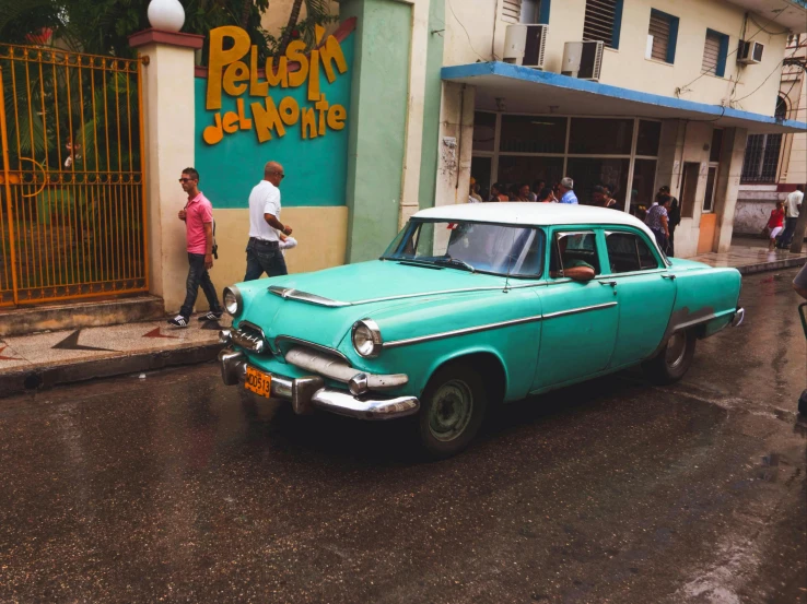 a vintage blue car is parked in front of a restaurant