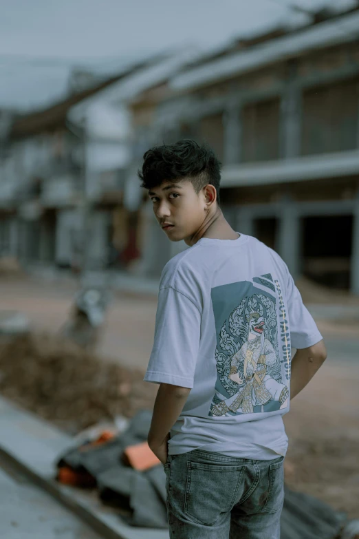 a young man standing by the road next to a bench