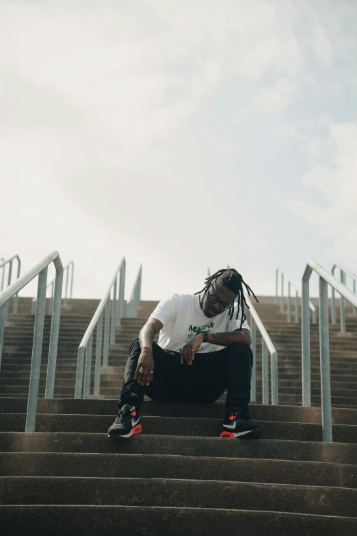 a man with dreadlocks sitting on some stairs